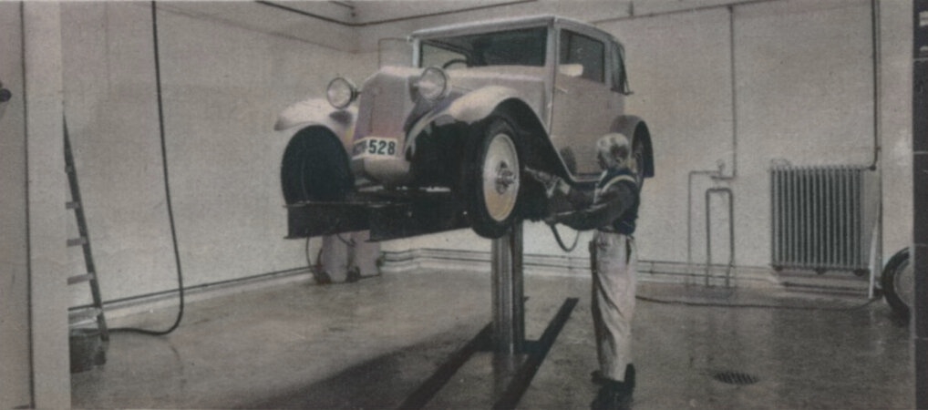 Promazávání čepů v garážích Standard na Brandlově ulici v roce 1933 (kolorovaná dobová fotografie)